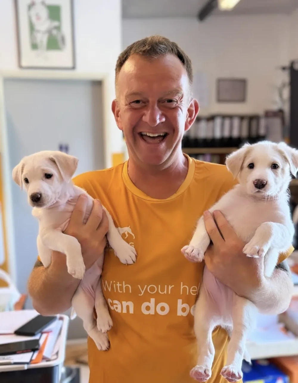 Kevin Marr smiling, holding two rescued puppies