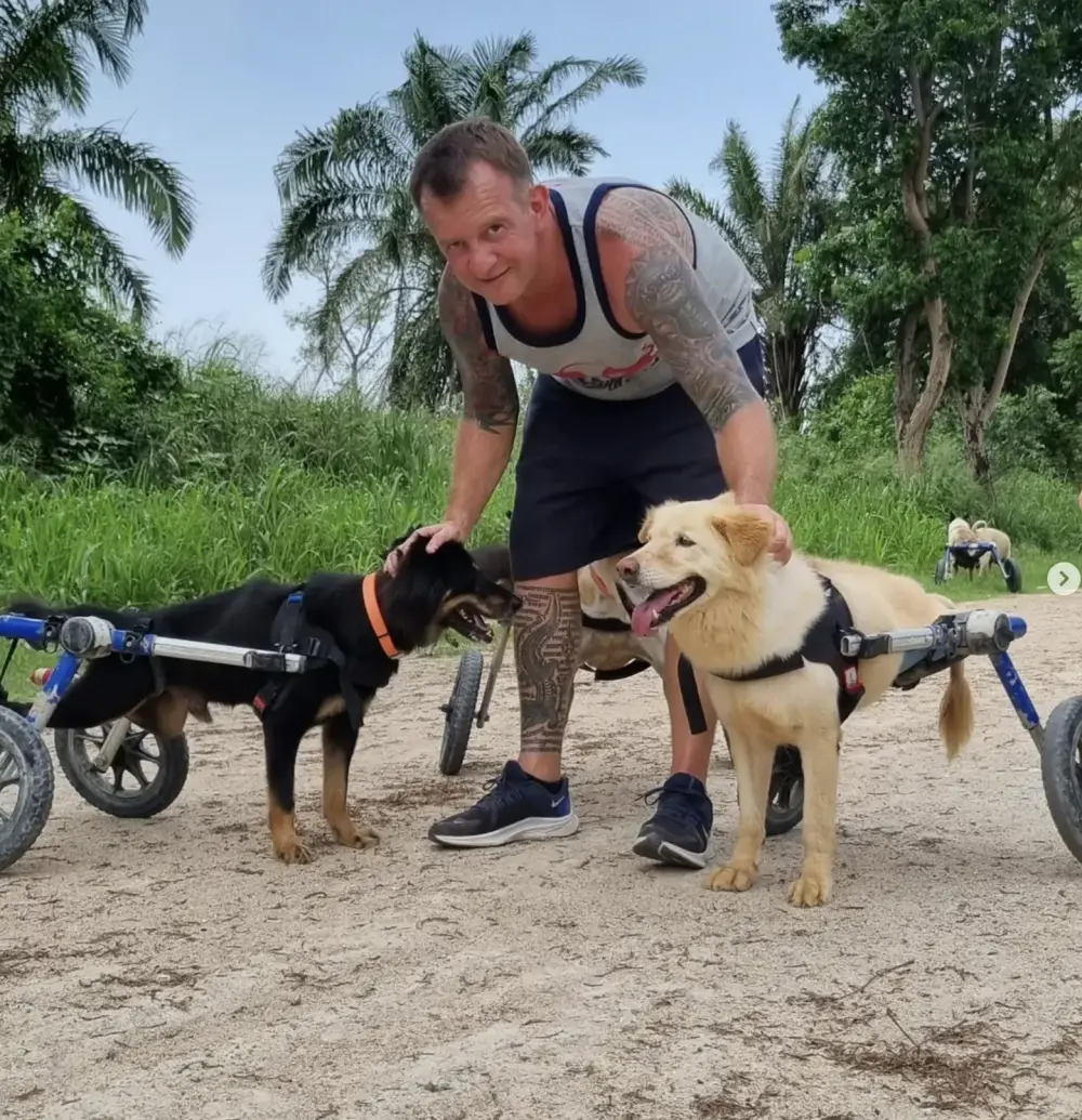 Kevin Marr in Thailand with two rescued dogs in wheelchairs