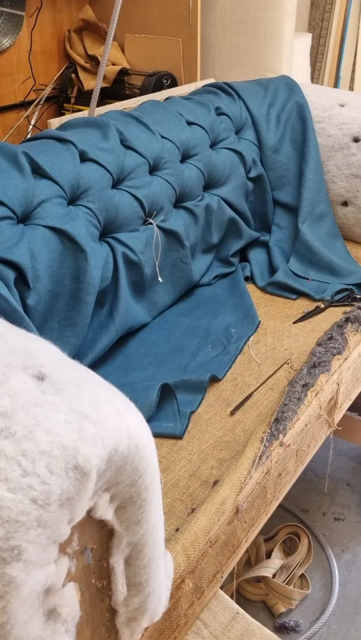 Hand-tied deep buttoning drawn into teal fabric, forming the diamond pattern