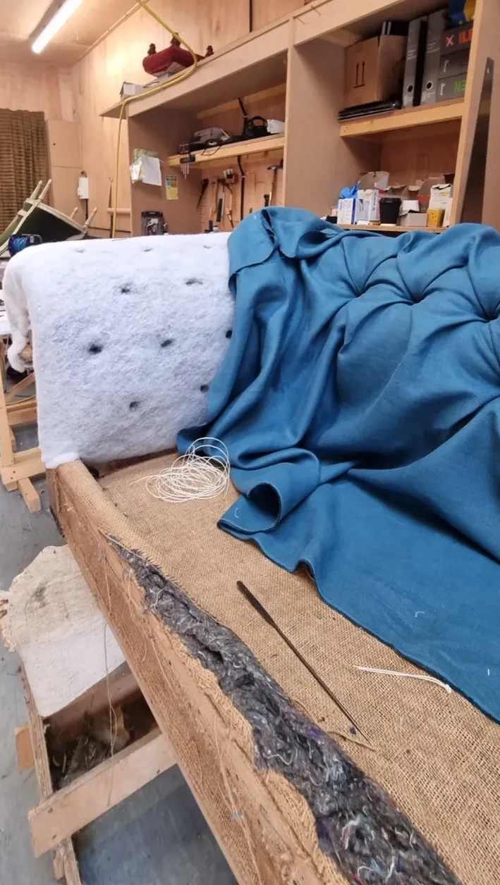 A buttoned piece in progress on the workbench, the padding dimpled by hand-tied buttons