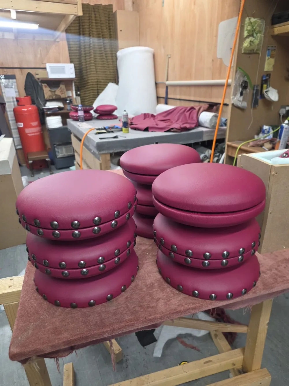 Stacks of round, stud-trimmed burgundy leather stools upholstered for the Scotch Whiskey Experience