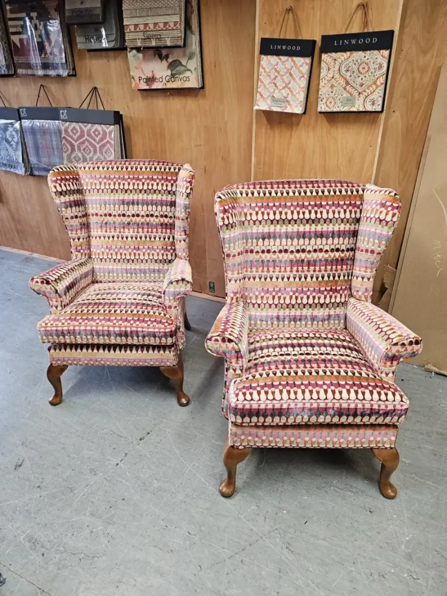 A pair of antique wingback armchairs reupholstered in a multicoloured raised velvet, in the workshop