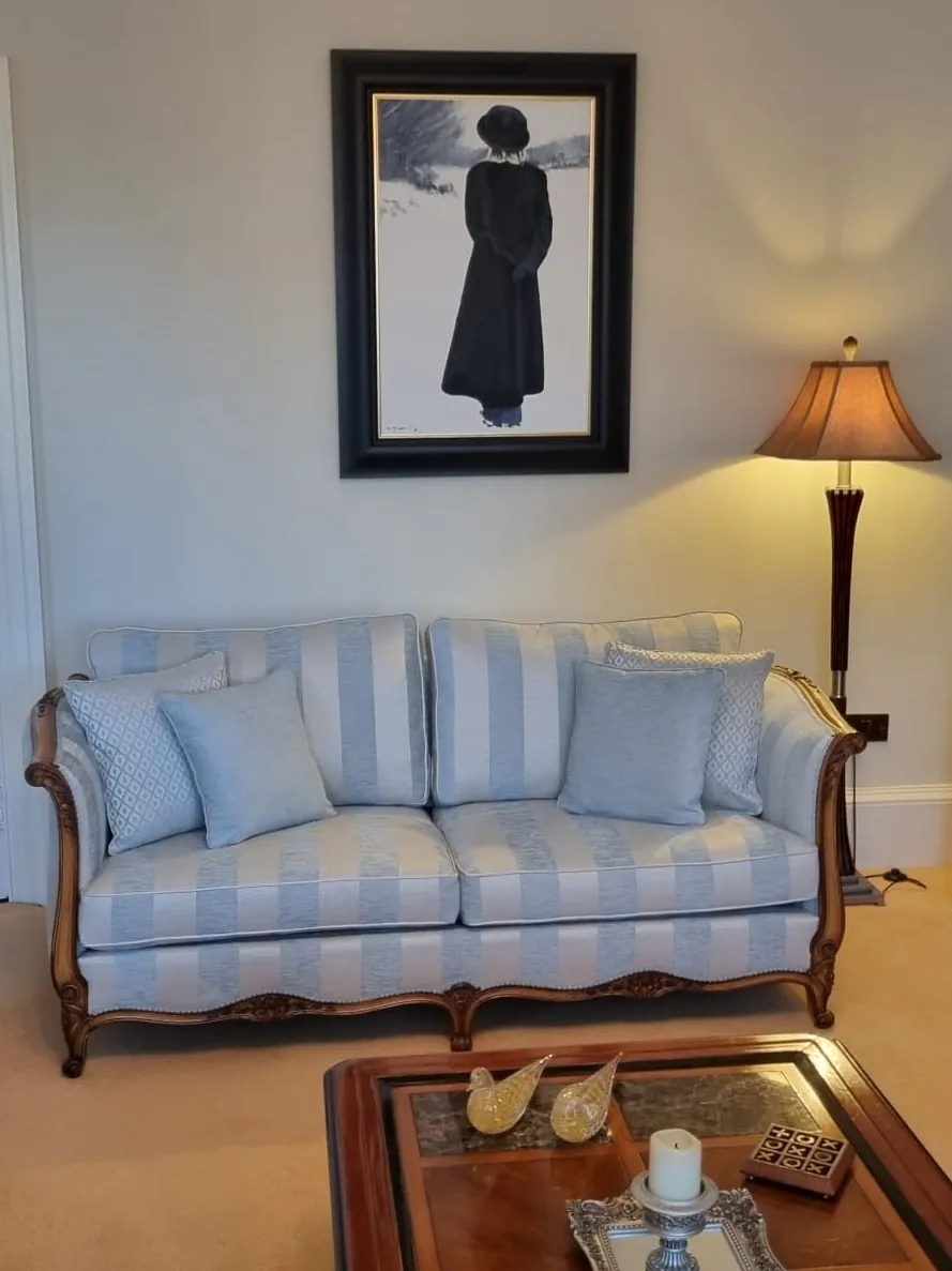 A carved-frame sofa reupholstered in a blue and cream stripe fabric