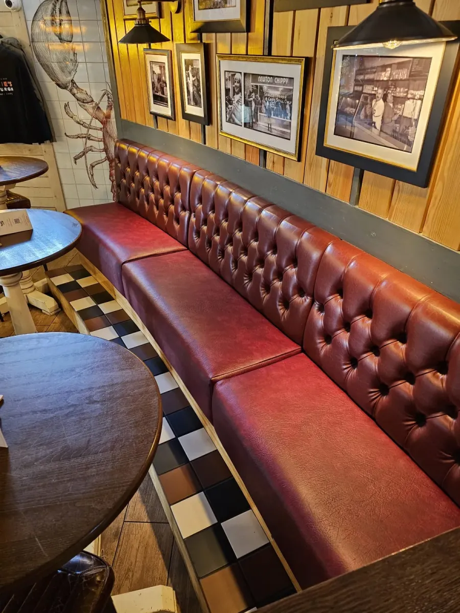 Deep-buttoned oxblood leather banquette bench seating in a bar and restaurant