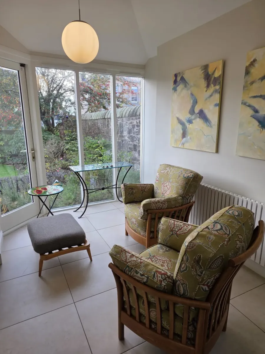 Ercol wooden-framed armchairs reupholstered in a green floral print linen