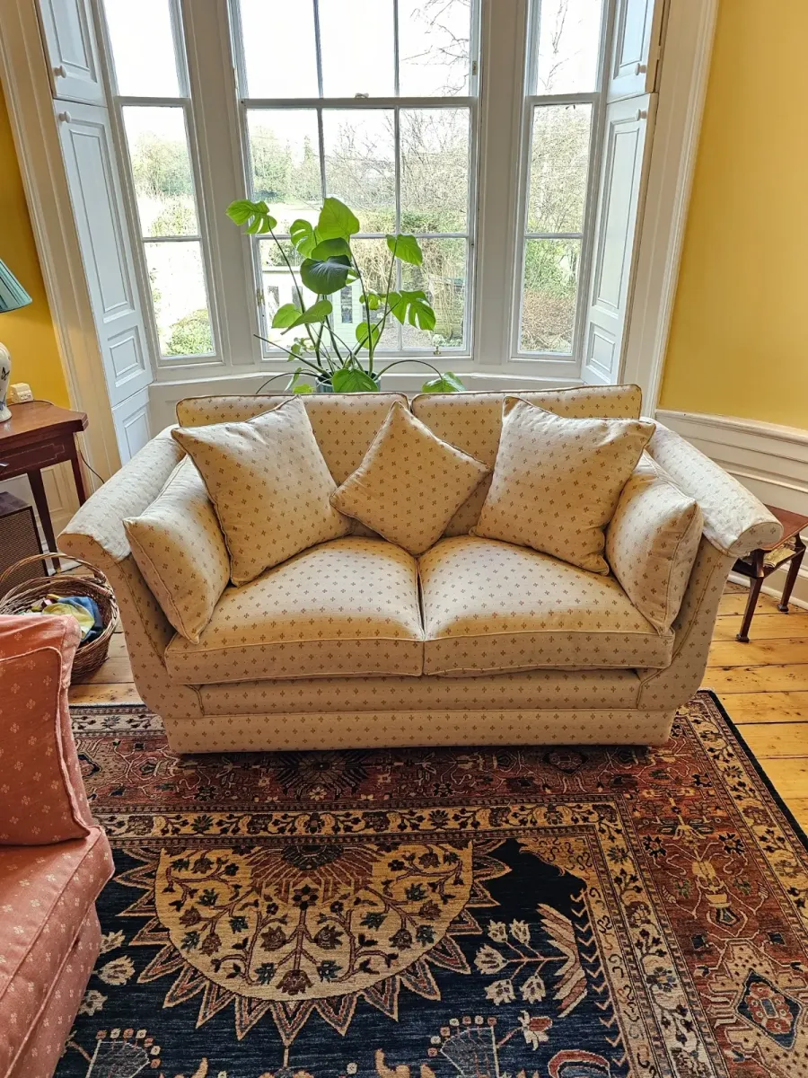 Traditional sofa reupholstered in a patterned weave, set in a bay window
